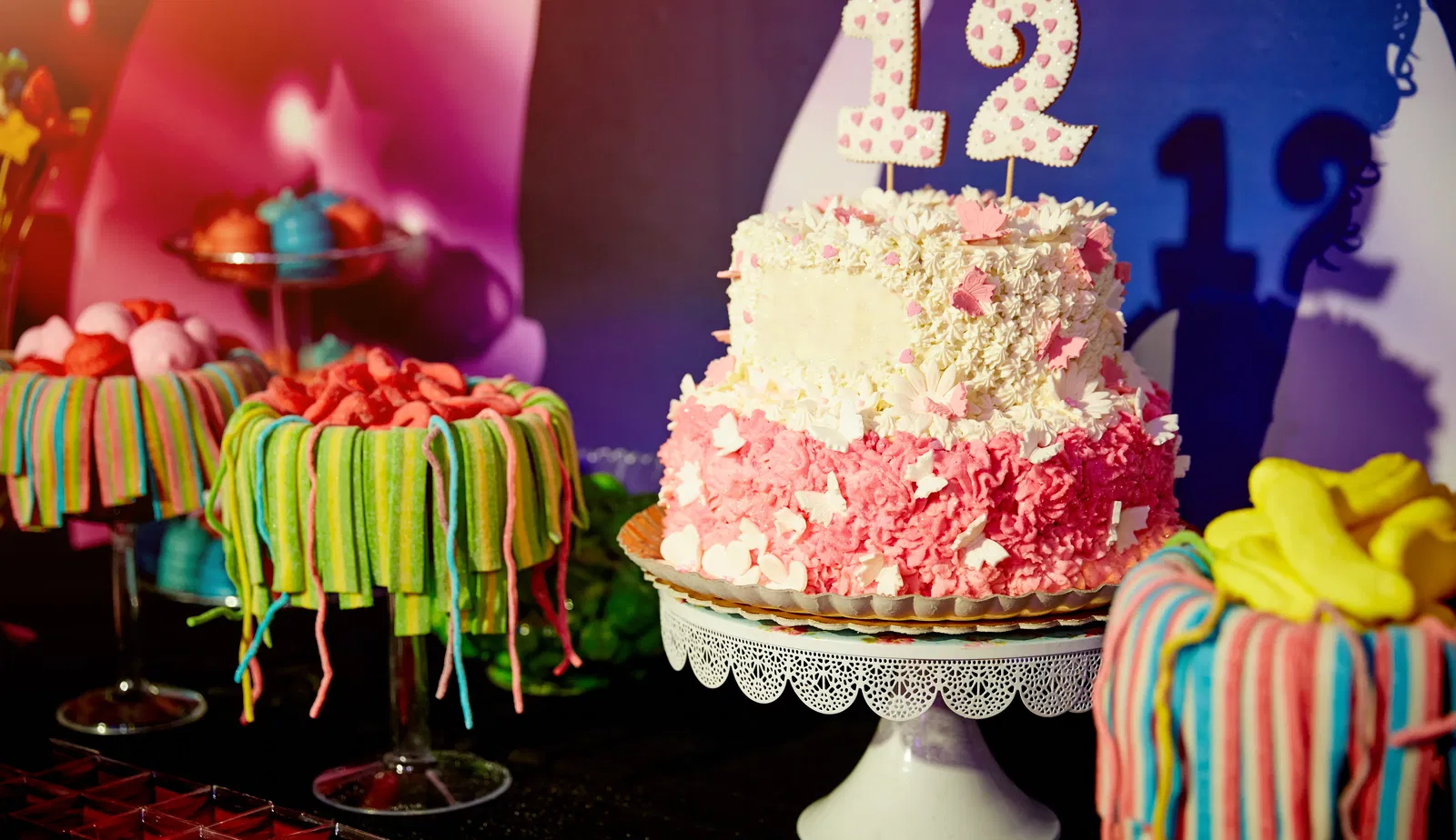 A cake on a festive table that has a decoration with the number 12.