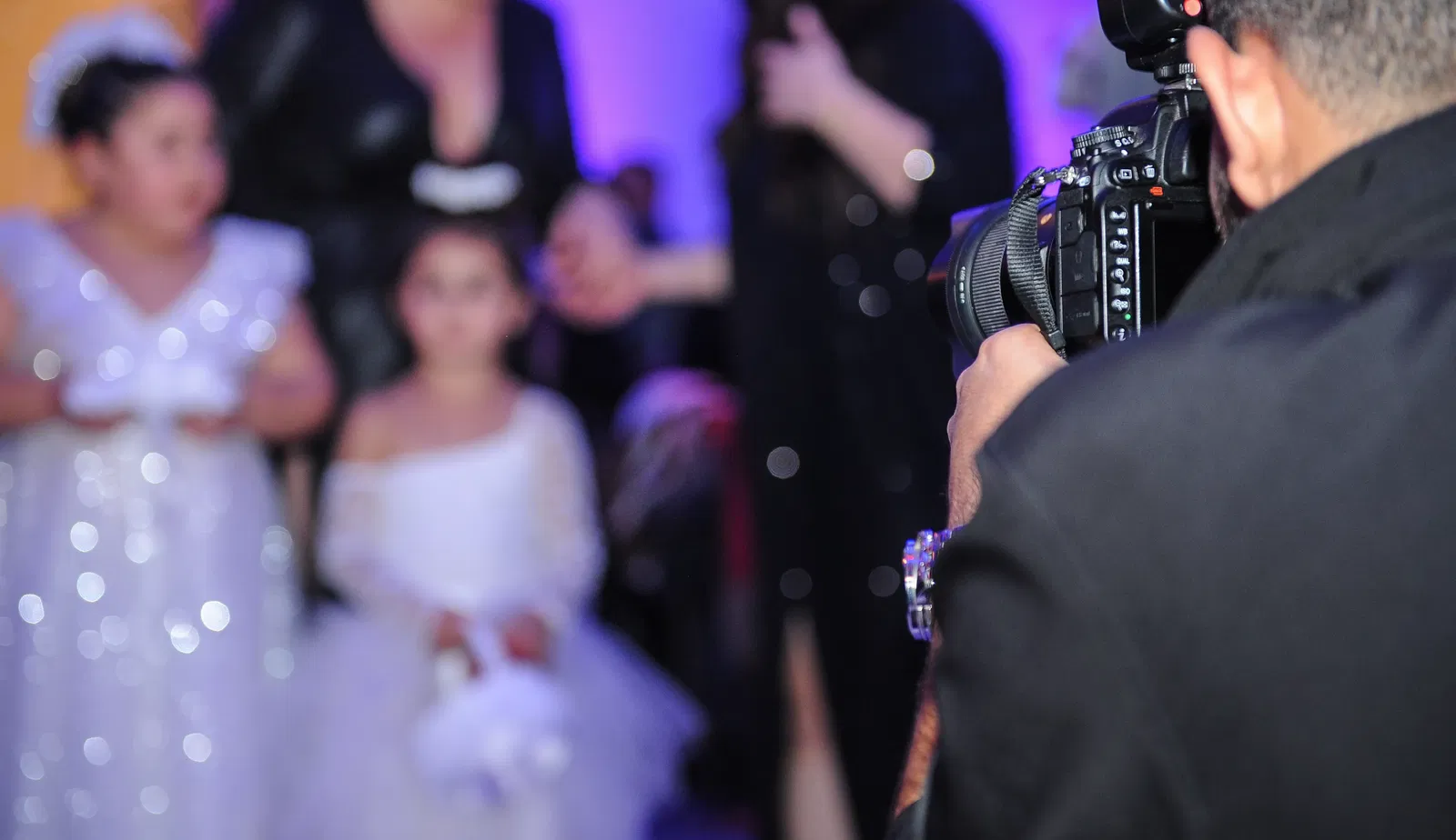 A photo of a cameraman photographing 2 young girls for their Bat Mitzvah.