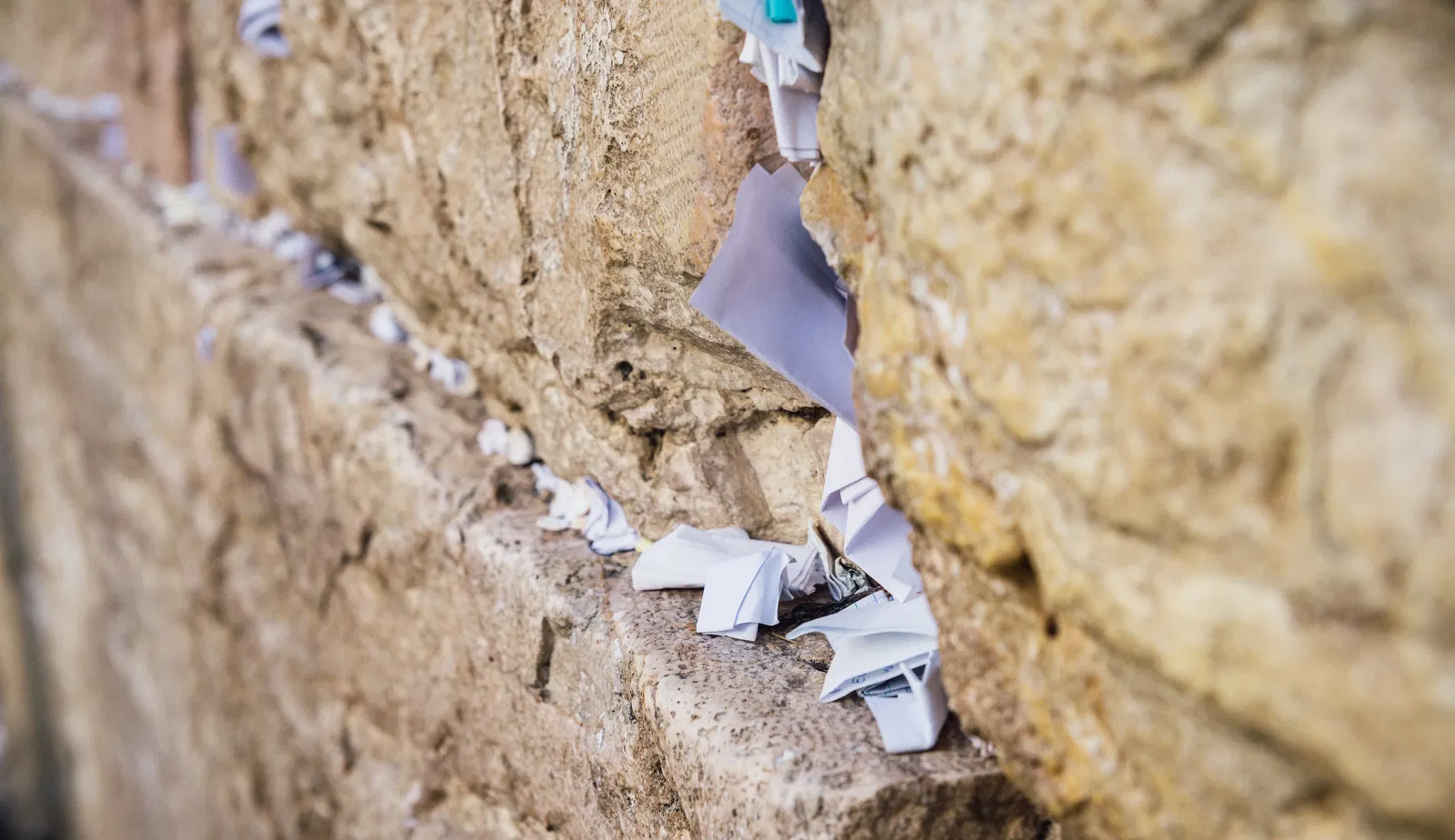 A photograph of a lot of notes stuck inside the cracks of the Western Wall.