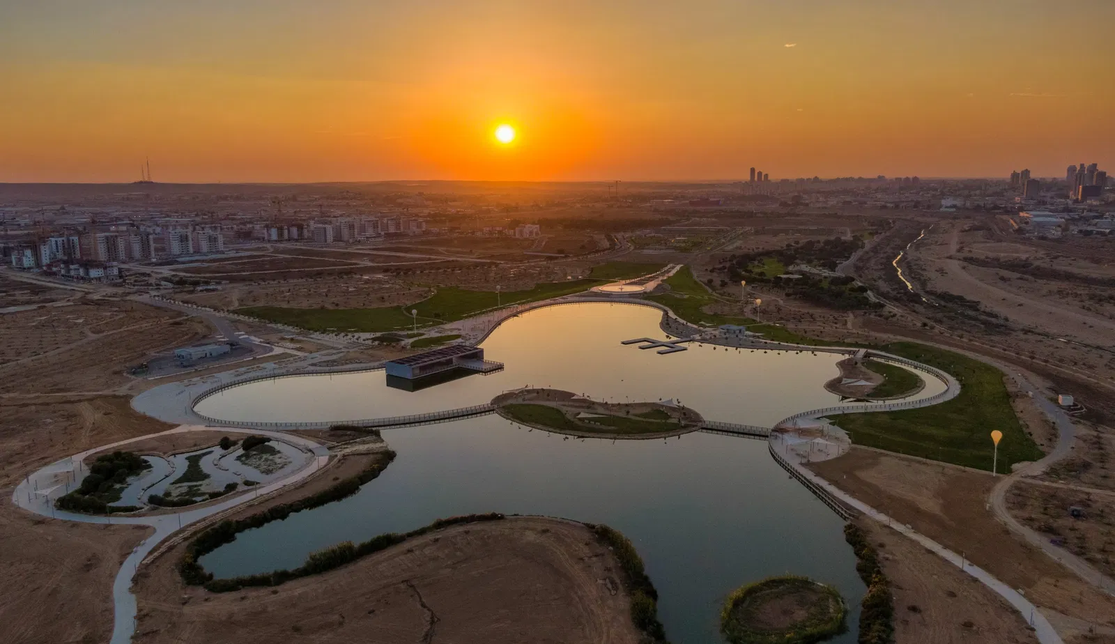 A drone view of an artificial lake in Be'er Sheva during sunset.