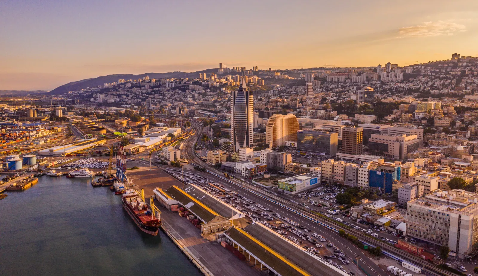 נמל המטען של חיפה ונוף העיר בשקיעה מנקודת מבט אווירית.